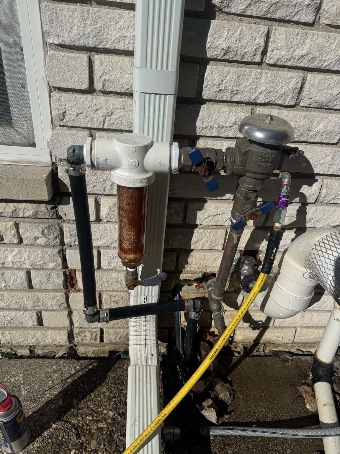 Compressor hose connected to exterior irrigation plumbing during a 15-zone well-pump sprinkler winterization in Shelby Township